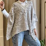 Ruana tejida de punto en color gris, con diseño amplio y envolvente, escote en V y delicados detalles bordados a mano con perlas y abalorios alrededor del cuello.