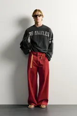 Sudadera cropped fit de color negro con efecto lavado vintage, cuello en V y manga larga. Presenta estampado con texto "LOS ANGELES" y el número "17" en parches acolchados en el frente, además de bandas grises en las mangas.