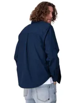 Camisa de manga larga de popelina color azul marino, de corte clásico con cuello camisero, cierre frontal con botones y bolsillo en el pecho con etiqueta de la marca Caterpillar. Incluye sistema para convertir las mangas en cortas.