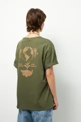 Remera negra de corte oversize con cuello redondo y manga corta. Presenta un pequeño estampado dorado en el pecho con la frase "love earth" y un símbolo de hojas.
