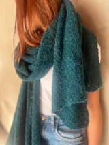 Chal de punto bouclé color marrón claro, hecho de 100% baby alpaca. Tejido suave, esponjoso y cálido, ofrece una textura envolvente y lujosa.