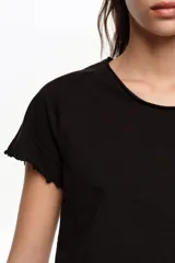 Remera corta de corte ajustado en color blanco, confeccionada en algodón orgánico. Presenta escote redondo, mangas cortas raglán y terminaciones con ondas en el cuello, mangas y dobladillo.