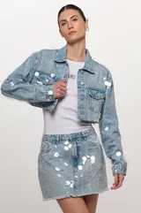 Falda vaquera de corte recto, confeccionada en denim celeste, adornada con maxi lentejuelas transparentes bordadas y detalle de flecos en el ruedo.