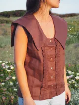 Blusa sin mangas de lino color blanco, con cuello marinero grande y detalles de encaje en el cuello y a lo largo de la botonadura frontal.