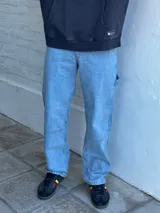 Jean azul claro de corte amplio, estilo carpintero, con pespuntes en contraste y cierre en el tobillo.