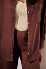 Camisa oversize color marrón, confeccionada en mezcla de viscosa y lino, con cuello clásico, cierre frontal con botones y un bolsillo aplicado en el pecho.