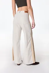 Pantalón de pierna ancha con acabado brillante, confeccionado en lino. Presenta un diseño de tiro medio con cierre de botón y cremallera, bolsillos traseros y etiqueta de marca en la cintura.