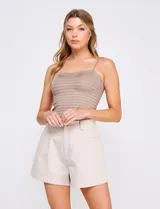 Top crop de punto elastizado color beige, con escote recto y tirantes finos regulables. Presenta una trama texturada con franjas horizontales.