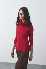 Polera de cuello alto holgado, manga larga y diseño de tejido fino con aberturas laterales en el ruedo.