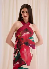 Vestido largo fluido de gasa color crudo con estampa floral en tonos rojos y fucsias, con escote halter cruzado de cuero.