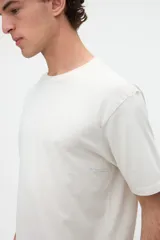 Remera de manga corta color blanco off-white, de calce clásico en tejido jersey de algodón. Presenta un gran diseño estampado en la espalda con un recuadro celeste que incluye las leyendas "WILD OCEAN" y "SALTY SOUL" junto con gráficos de olas y estrellas en tonos rosados y amarillos.