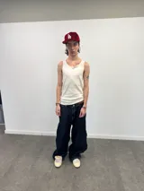 Pantalón de jean azul raw con diseño de corte versátil, ajustable mediante cierres laterales que revelan un panel interior rojo. Presenta una estampa gráfica de gran tamaño en la parte trasera con detalles bordados, costuras reforzadas y etiqueta de cuero en la cintura.