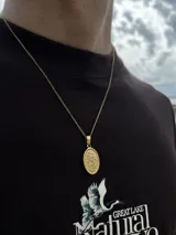Cadena de eslabones finos en color dorado con dije ovalado grabado.