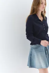 Pollera mini de denim de algodón rígido, color celeste claro con efecto lavado. Diseño acampanado con cintura estándar, cierre frontal con botón y cinco bolsillos.