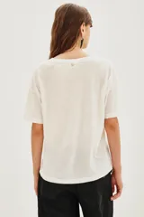 Remera de algodón blanca, corte holgado, con cuello redondo. Presenta un estampado frontal grande con la palabra "VINYL" en rojo y la ilustración de un disco de vinilo en negro y rojo.