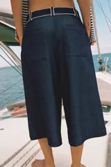 Bermuda ancha de tiro alto, confeccionada en denim color azul, con pinzas delanteras y detalles de vivos a contraste. Cuenta con cierre frontal con cremallera y botón.