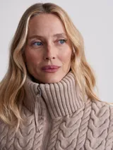 Campera puffer beige con cuello alto acanalado, cierre frontal con cremallera y bolsillos laterales.