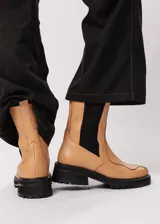 Bota de cuero color camel, estilo Chelsea, con elásticos laterales negros y suela track negra.