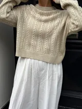 Sweater color crema tejido con diseño en ochos y cuello redondo.