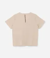 Blusa de manga corta color beige, confeccionada en tela texturizada. Presenta cuello redondo con detalle de pespuntes y cierre trasero con botón en forma de lágrima.