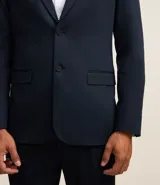 Saco de traje masculino de corte slim, confeccionado en poliviscosa con textura acanalada leve. Presenta cuello con solapa, cierre frontal con botones, mangas largas y bolsillos laterales. Incorpora tecnología performance para mayor respirabilidad y secado rápido.