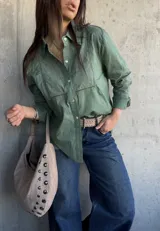 Camisa de manga larga color verde militar, con cuello camisero, cierre frontal de botones y detalles de bordados y calados en el frente y las mangas.