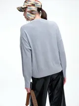 Sweater de punto color negro, con cuello redondo, hombros caídos y terminaciones acanaladas en puños y ruedo. Presenta un diseño de calce relajado y tejido suave.