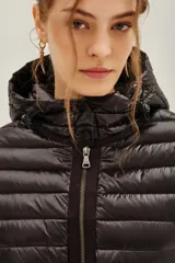 Campera puffer negra con capucha, cierre frontal con doble cremallera y diseño entallado en la cintura.
