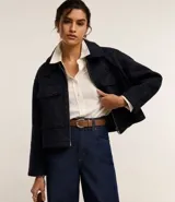 Campera corta azul marino de tejido boucle con cuello inglés, cierre frontal con cremallera y bolsillos grandes con solapa en el pecho.