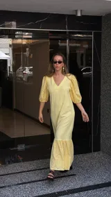 Vestido largo color amarillo pálido, con escote en V, mangas cortas abullonadas con detalle de calado y ruedo con volantes y calado.