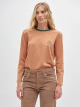 Remera de manga larga con cuello redondo y estampado a rayas horizontales en tonos marrón y negro. Tiene un logo bordado en el pecho de color rojo.