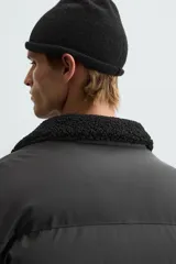 Cazadora acolchada de hombre con acabado engomado, cuello subido con interior de borreguillo, cierre frontal de cremallera, bolsillos laterales con cremallera y puños y bajo elásticos.