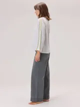 Remera de manga larga color gris claro, con detalle de franjas laterales en contraste color amarillo en las mangas. Presenta un diseño holgado y moderno.