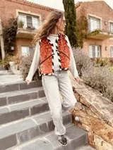 Chaleco color crema con ribete amarillo, de corte recto y sin mangas.