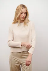 Buzo de punto color beige, con cuello redondo y manga larga.