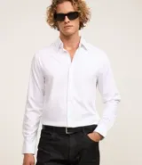 Camisa de vestir blanca, corte slim, cuello clásico, manga larga y abotonadura frontal.
