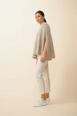 Poncho de tejido de punto con cuello alto y aberturas laterales para los brazos, de diseño holgado y minimalista.