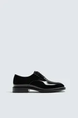 Zapato de vestir tipo derby color negro acharolado, con horma en punta y suela con ligero tacón.