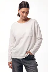 Remera de manga larga color blanco, confeccionada en algodón, con corte relajado, escote redondo y bolsillo frontal en el pecho.