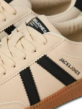 Championes de diseño urbano, color beige con franjas laterales negras y suela de goma marrón.