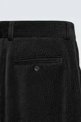 Pantalón de corte wide fit confeccionado en pana de algodón color marrón oscuro. Presenta bolsillos frontales, bolsillos traseros de vivo con botón y cierre frontal con cremallera y botón.