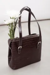 Cartera de hombro estructurada color negro, confeccionada en 100% cuero vacuno con textura en relieve tipo reptil. Cuenta con asas largas ajustables mediante hebillas metálicas plateadas, cierre superior y el logo de la marca grabado en la parte frontal.