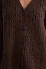 Cardigan de punto con diseño de trenzas, color beige, con escote en V, cierre frontal de botones negros y mangas largas con puños acanalados.