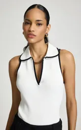 Top polo Pat de la marca Le Lis Blanc, de tejido acanalado en color blanco con detalles de ribetes negros en el cuello y la solapa. Presenta un diseño sin mangas, corte al cuerpo y escote en V profundo con cuello tipo polo.