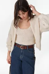 Cardigan crop de punto color crudo, con frente abierto sin botones y mangas largas abullonadas.