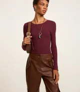 Suéter de punto acanalado color beige, con cuello redondo y mangas largas. Confeccionado en tejido tricot con textura suave y ajuste al cuerpo.