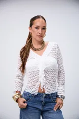 Blusa blanca de encaje con cuello en V, volados frontales y manga larga.