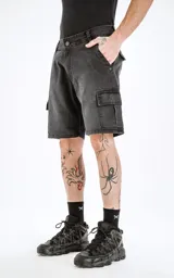 Bermuda cargo de denim negro lavado, de calce regular, con cinco bolsillos y bolsillos cargo laterales. El ruedo es desflecado.