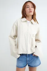 Campera rústica de color beige con diseño a rayas verticales, cuello camisero y cierre frontal de cremallera metálica.