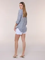 Blusa de silueta relajada con textura tramada, color azul con rayas verticales en tonos rosados, celestes y amarillos. Cuenta con cuello mao abierto en V y mangas tres cuartos amplias con pequeña abertura lateral en el puño.